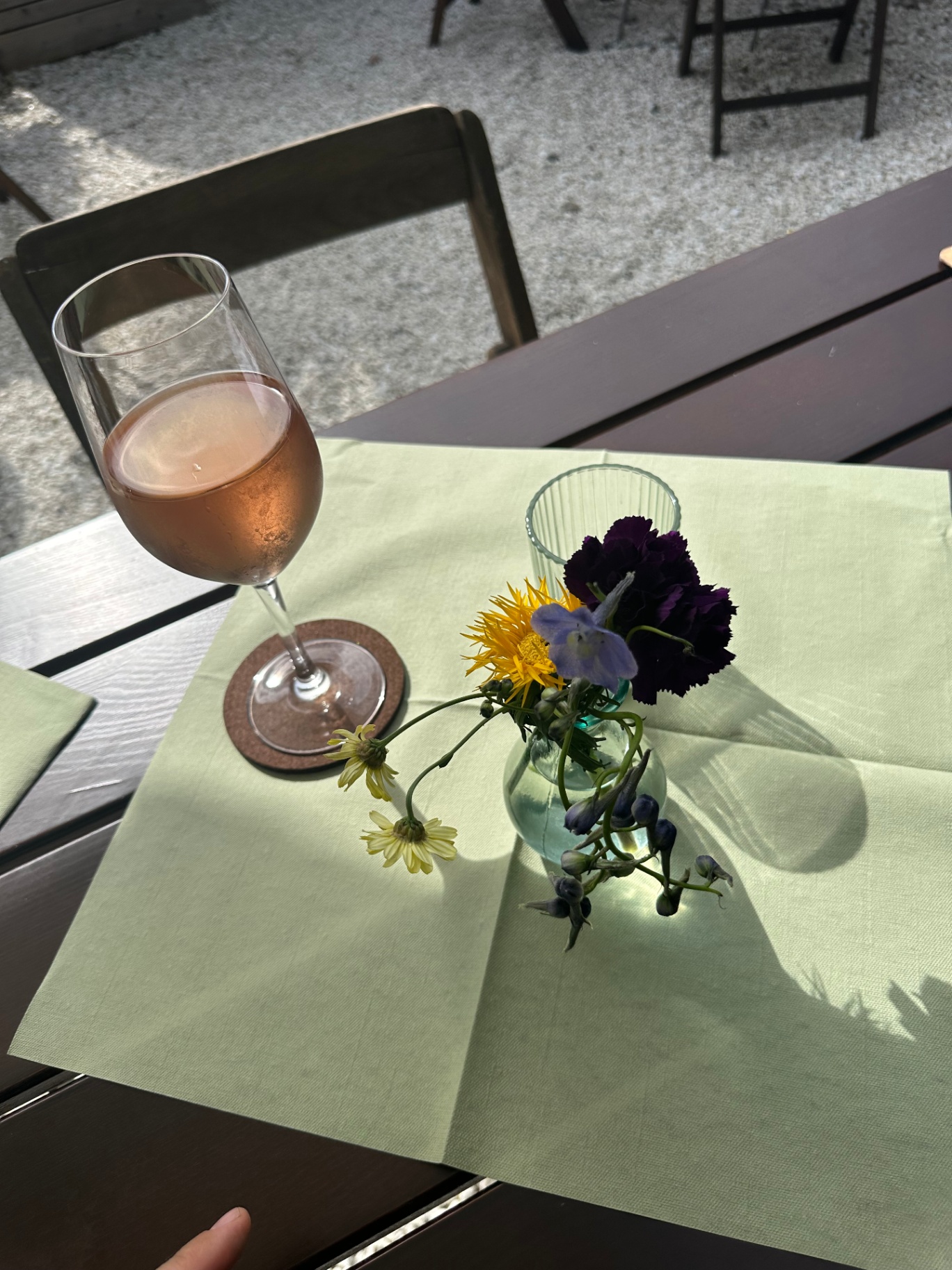 Roséwein und Blumenvase auf dem Tisch im Garten